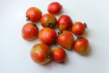 Fresh ripe strawberry guavas arranged on a white surface. Vibrant red tropical fruits showing natural texture and color. Exotic edible fruit commonly known as Psidium cattleianum.