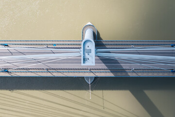 A drone shot captures a symmetrical aerial view of a modern bridge crossing a wide river. The...