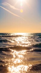 Golden sunlight glints on a tranquil ocean at sunset, painting the water with a warm, reflective glow.