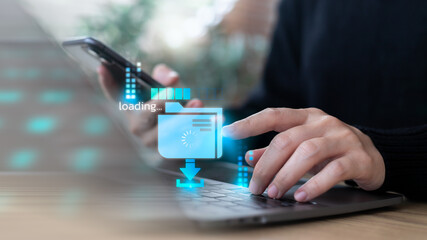 Business using a laptop and smartphone with a hologram of cloud file download, data transfer,...