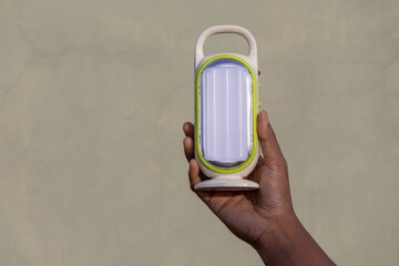 Close-up of a female hand holding a compact, rechargeable LED light. The powerful emergency light...