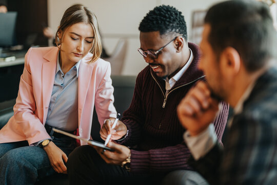 Business people working together in a collaborative office meeting, sharing ideas and using a tablet to brainstorm innovative solutions.