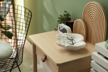 Wooden side table with stylish decor near green wall indoors, closeup