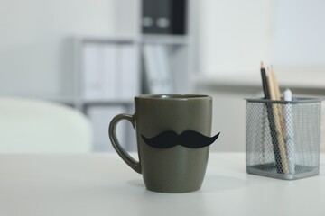 Happy Father's Day. Cup with paper moustache on white table indoors
