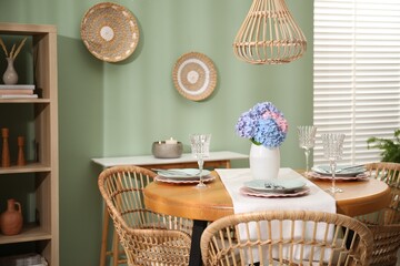 Stylish setting with plates and vase of flowers on wooden table in dining room. Interior design