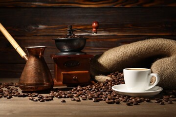 Aromatic coffee in cup, beans, cezve and grinder on wooden table