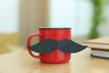 Happy Father's Day. Cup with mustache and notebooks on wooden table indoors, closeup