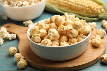 Tasty popcorn and corncob on light blue wooden table, closeup
