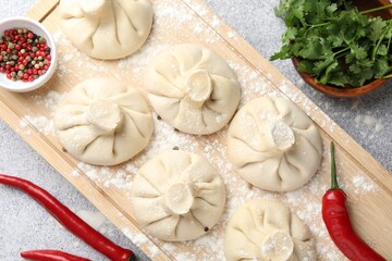 Uncooked khinkalis (dumplings) and spices on light grey table, flat lay