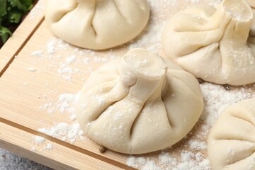 Uncooked khinkalis (dumplings) on wooden board, closeup