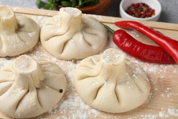 Uncooked khinkalis (dumplings) and chili pepper on table, closeup