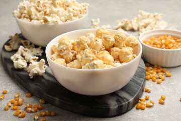 Tasty popcorn and corn kernels on light grey table, closeup