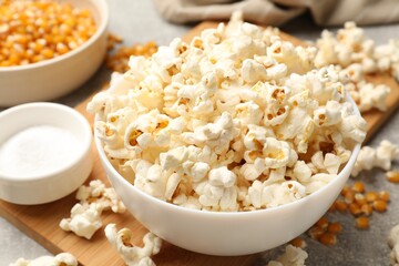 Tasty popcorn and corn kernels on light grey table, closeup