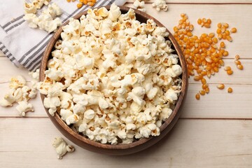 Tasty popcorn and corn kernels on light wooden table, flat lay