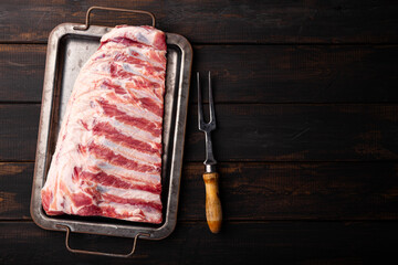Raw pork ribs on a black wooden background top view copy space for text, raw pork meat