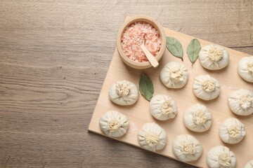 Uncooked khinkalis (dumplings) and spices on wooden table, top view. Space for text