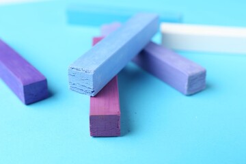 Colorful chalk pastels on light blue background, closeup