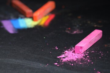 Pink chalk pastel on black table, closeup