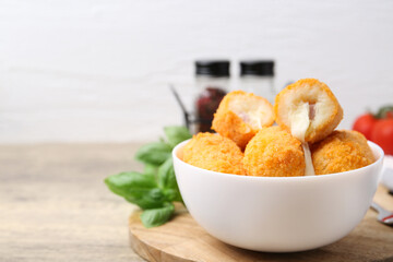 Delicious fried croquettes in bowl on wooden table, closeup. Space for text