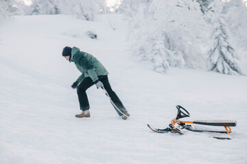 Girl pulling snowracer uphill in snowy forest during winter