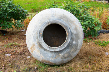 Old cement water jar placed outdoors in a rural area, used for storing rainwater or household water. Traditional water container in Asian countryside, symbol of rural lifestyle, agriculture, and susta