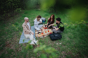 Friends relaxing on a picnic blanket in the forest, surrounded by nature. The scene includes fresh...