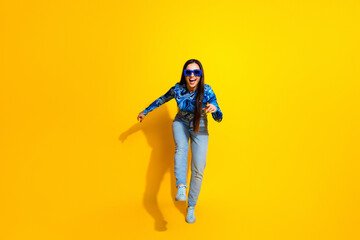 Cheerful woman posing playfully in modern fashion against vibrant yellow background, expressing energy and positivity