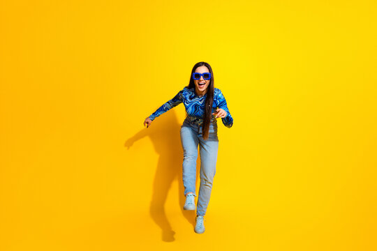 Cheerful woman posing playfully in modern fashion against vibrant yellow background, expressing energy and positivity - Powered by Adobe