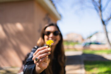 Woman holding a dandelion flower with a blurred background in a sunny day at the park