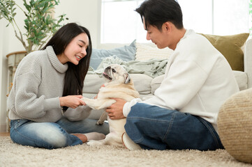 Couple Enjoys Playful Moments With Their Pug in a Cozy Living Room Setting During the Afternoon
