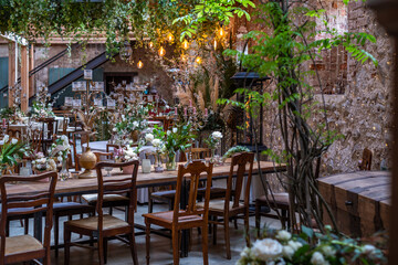 Elegant wooden table adorned with floral decorations and rustic chairs, creating a warm ambiance for a celebration in a beautifully designed indoor space with greenery