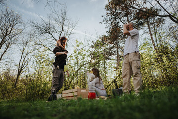 A family spending time together during a picnic outdoors, surrounded by trees and nature. The...