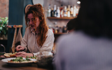 A woman with red hair prepares a meal in a relaxing bar environment with warm lighting. A blurred...