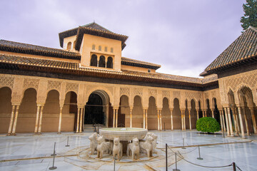 Fototapeta premium La Alhambra, Spain - The Court of the Lions features a marble fountain with twelve lion statues and slender columns under ornate Moorish arches.