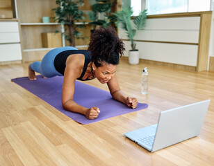 Portrait of a fit black girl young woman exercising practicing yoga or fitness watching online...