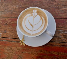 A cup of coffee with latte art on the wood table