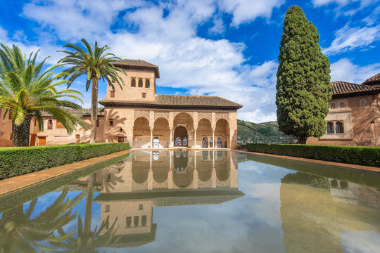 Enjoy the serene Jardines de Partal gardens in La Alhambra Spain, featuring a stunning reflection of arches and palm trees in a tranquil pool.