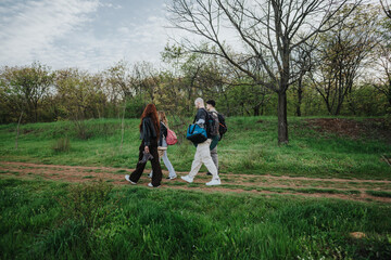 Family members walking together on a trail surrounded by lush greenery and trees. The outdoor scene...