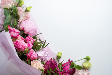Bouquet of pink flowers on a white table, top view. Beautiful floral composition of roses, peonies, eustoma and hydrangea, in pink packaging. Wedding bouquet