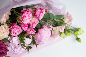 Bouquet of pink flowers on a white table, top view. Beautiful floral composition of roses, peonies, eustoma and hydrangea, in pink packaging. Wedding bouquet