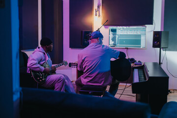 Diverse musicians working together in a studio, creating and producing music. The setting includes guitars, a computer screen, and other equipment essential for music production and collaboration.