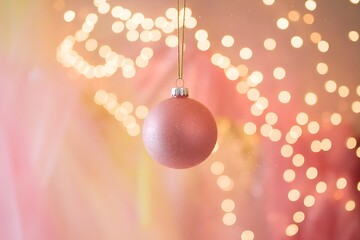 A Delicate Pink Christmas Ornament Hanging Against a Festive Bokeh Background
