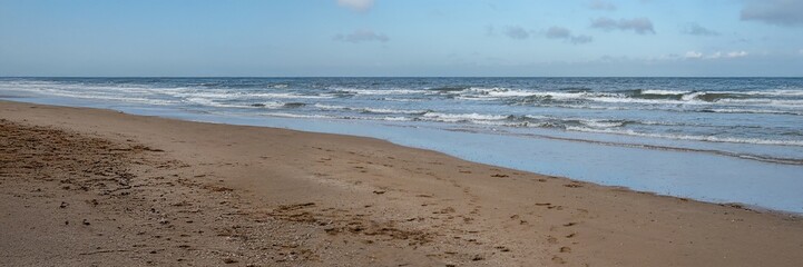 Obraz premium Waves gently rolling onto sandy beach on cloudy day