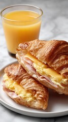 Tasty croissant filled with ham and egg paired with a glass of fresh orange juice, ideal for a simple breakfast or snack