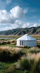 Nestled in a picturesque valley, a yurt stands peacefully with mountains in the background while a horse grazes nearby under a sunny sky