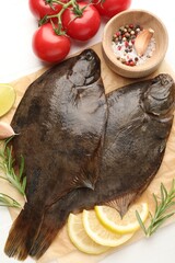 Fresh raw flounder fish and ingredients on white wooden table, flat lay. Seafood