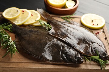 Fresh raw flounder fish and spices on black wooden table, closeup. Seafood