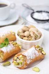 Delicious cannoli with cheese, pistachios, powdered sugar and mint on table, closeup