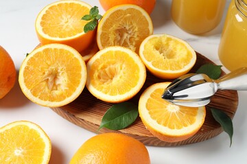 Squeezer, oranges and mint on white table, closeup. Making fresh juice