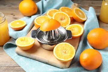 Freshly squeezed orange juice, fruits, juicer and towel on wooden table
